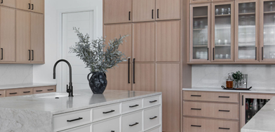 Soft white kitchen island with warm wood perimeter cabinets. Black hardware on all cabinets.